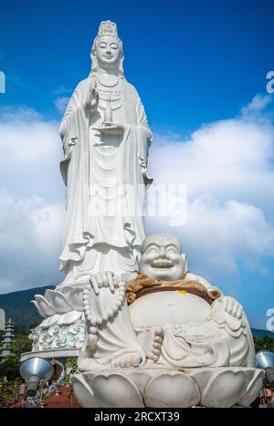 Una statua Budai, o Buddha ridendo, davanti alla statua gigante di Avalokitesvara Bodhisattva nella pagoda buddista Ling Ung Bai Buc in Son tra, Danang, Foto Stock