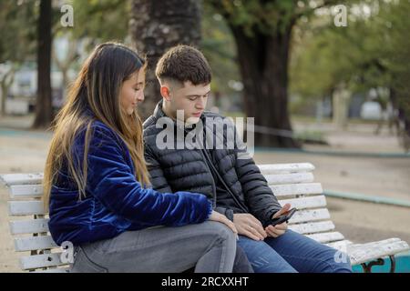 Giovane coppia seduta sulla panchina in una piazza. Foto Stock