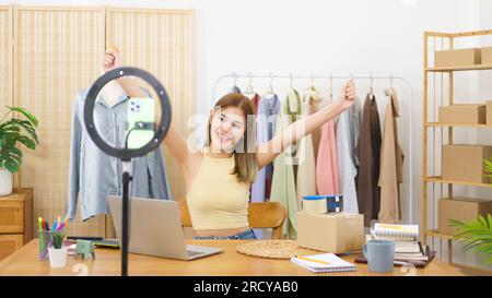 Concetto di vendita in linea, riuscito stilista delizioso con i vestiti di vendite effluenti in tensione. Foto Stock