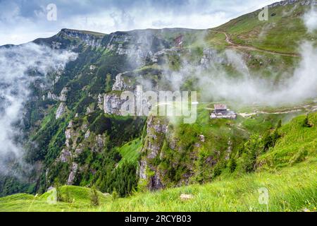 Capanna e montagne coperte di nuvole lungo il percorso escursionistico da Busteni a Caraiman Peak, nei Carpazi, Romania. Foto Stock