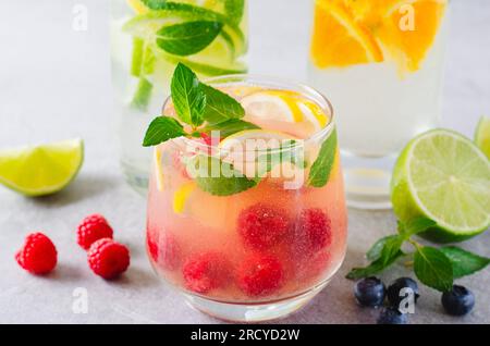 Set di bevande estive, frutta, agrumi e frutti di bosco, limonate rinfrescanti o cocktail su sfondo luminoso Foto Stock