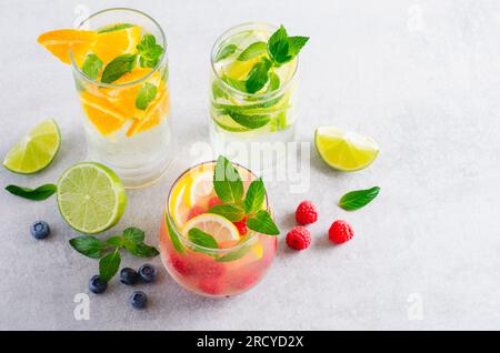 Set di bevande estive, frutta, agrumi e frutti di bosco, limonate rinfrescanti o cocktail su sfondo luminoso Foto Stock