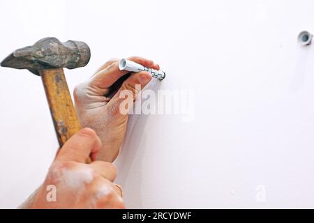 martellare gli ancoraggi a muro, inchiodare la striscia di quercia nel corridoio Foto Stock
