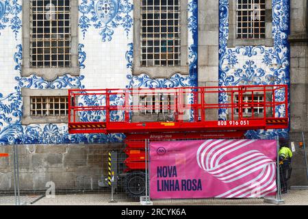 Ascensore a forbice piattaforma sopraelevata parcheggiata accanto alla parete laterale coperta di piastrelle azulejo della chiesa di Igreja do Carmo, Porto / Oporto, Portogallo Foto Stock