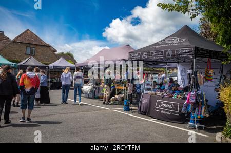 Le persone curiosano tra le bancarelle di un mercato artigianale del villaggio in una soleggiata giornata estiva a Billingshurst, West Sussex, Regno Unito. Foto Stock