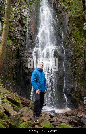 Attrazione turistica della Germania - cascate di Burgbach vicino Schapbach, Foresta Nera, Baden-Wurttemberg, Germania. Uomo escursionista in giacca blu standin Foto Stock