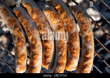 Cucinare succose salsicce grigliate al barbecue sul retro grigliando a carbone. Salsicce sul grill Foto Stock