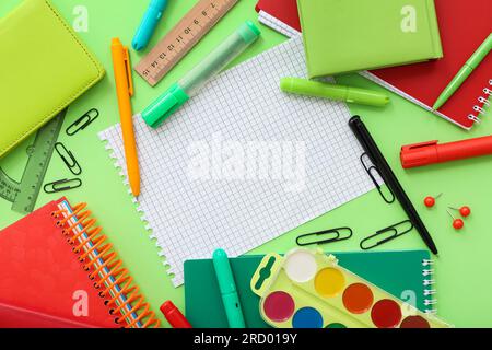 Cornice realizzata in cancelleria diversa con notebook vuoto su sfondo verde Foto Stock