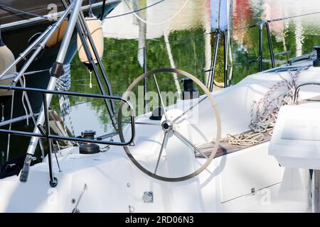 Vista parziale della barca da diporto bianca, yacht a vela con ampio volante, per scegliere il percorso come concetto per la navigazione in acqua tran Foto Stock