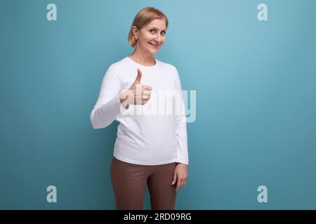 la donna bionda degli anni '50 con un maglione bianco mostra il suo dito super Foto Stock