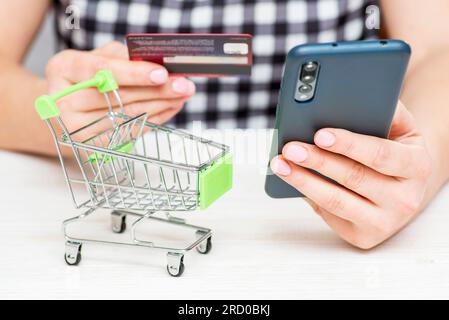 Una donna con carta di credito e telefono di plastica, che effettua un pagamento sicuro via Internet Foto Stock