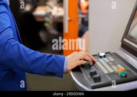 Ingegnere che lavora con la console di controllo CNC della macchina per tornio per la lavorazione dei metalli. Messa a fuoco selettiva. Foto Stock