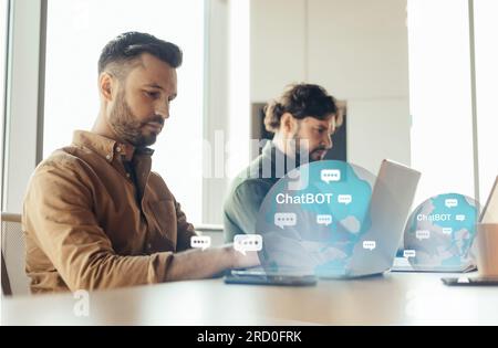 Dipendente IT concentrato che utilizza chatbot mentre lavora in team Foto Stock