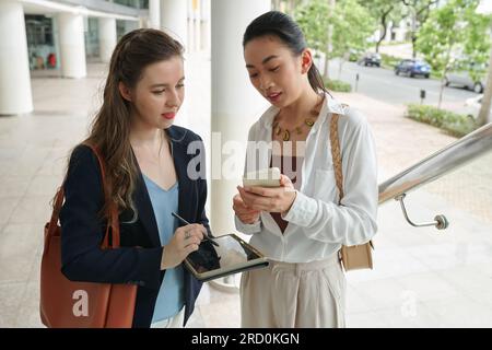 Giovani donne d'affari che discutono di orari e pianificano il lavoro quando si trovano all'aperto Foto Stock