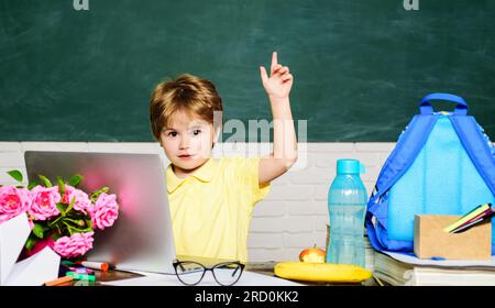 Sorridente scolaro che si diverte contro la lavagna. Prima volta a scuola. Ragazzo allievo della scuola elementare in classe. Bambino pronto a studiare Foto Stock