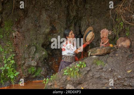donna indigena che fa un'offerta a dio all'interno di una laguna in una cerimonia a otavalo Foto Stock