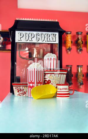 Home film sono così molto meglio con popcorn fresco! Il Popcorn siede nei supporti e scoop giallo si trova pronto per secondi. Foto Stock