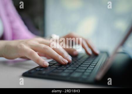 Primo piano sulle mani femminili che digitano sulla tastiera del notebook Foto Stock
