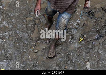 Un uomo cammina nel fango durante la pulizia della sua casa mentre l'acqua alluvionale del fiume Yamuna si ritira, al Yamuna Bazar di nuova Delhi. La gente del posto e le autorità trasportano un giro di pulizia nelle zone basse colpite dalle inondazioni per ridurre al minimo le malattie trasmesse dall'acqua. Ancora una volta il livello dell'acqua di Yamuna ha raggiunto 205,93 metri sopra il segno di pericolo di 205,33 funzionario ha detto. Il Rover Yamuna ha battuto un record di 45 anni e ha raggiunto il suo livello più alto di tutti i tempi di 208,65 il 2023 luglio dopo forti piogge e rilascio di acqua dallo sbarramento di Hathnikund ad Haryana. La gente del posto e le autorità effettuano una guida di pulizia in caso di alluvione Foto Stock