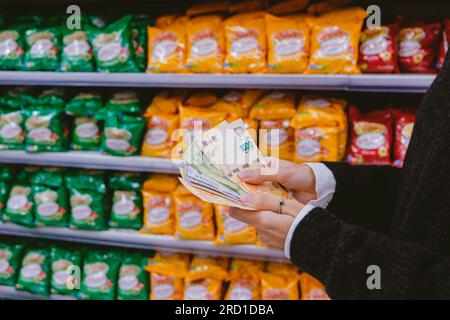 Donna che conta soldi - pesos argentini - nel supermercato. Foto Stock