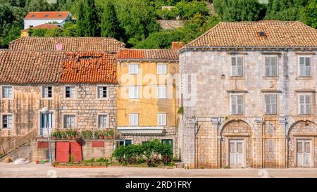 Case tradizionali in pietra lungo la strada sul lungomare nel pittoresco villaggio di Sipanska Luka sull'isola di Sipan, sulla costa dalmata in Croazia. Foto Stock