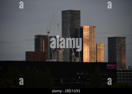 Manchester, Regno Unito. 18 luglio 2023. Luce dell'alba mentre il sole nascente inizia ad illuminare i blocchi della torre di Deansgate Square con gru a torre di fronte. Il Manchester City Council ha concordato piani per costruire più di 1.500 appartamenti in tutto il centro di Manchester, tra cui due nuovi grattacieli. Quasi 1.000 appartamenti saranno costruiti in due edifici a 51 piani in Great Jackson Street, accanto agli importanti edifici a torre di Deansgate Square. I critici hanno sostenuto che pochi di questi appartamenti saranno accessibili e più residenti eserciteranno pressioni sui servizi esistenti, come il servizio sanitario nazionale e le scuole. Credito: Terry Waller/Alamy Live News Foto Stock