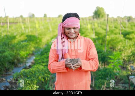 Felice agricoltore indiano, contadino che tiene il terreno in mano Foto Stock