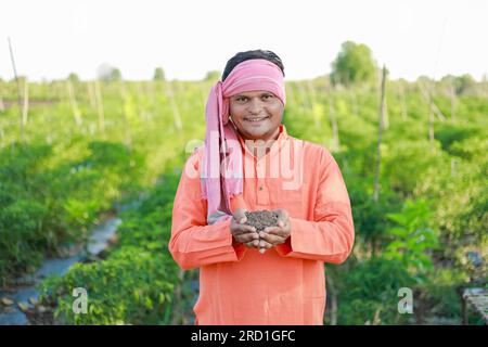 Felice agricoltore indiano, contadino che tiene il terreno in mano Foto Stock
