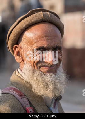 Lahore, Punjab, Pakistan - 11 10 2019: Ritratto ravvicinato all'aperto di un vecchio barbato sorridente che indossa il pakol tradizionale alla luce del sole del tardo pomeriggio Foto Stock