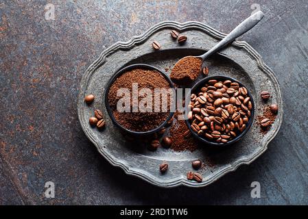 Chicchi di caffè e polvere di caffè appena macinata su fondo in pietra grigia primo piano Foto Stock