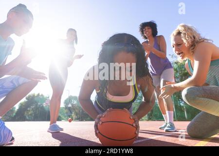 Felice e diversificato gruppo di donne che fanno push up con il basket e tifo sul campo da basket Foto Stock