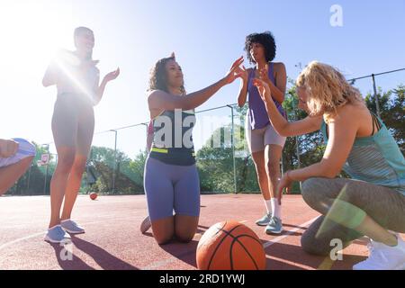 Felice e variegato gruppo di donne che applaudono con le mani e applaudono al campo da basket Foto Stock