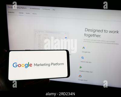 Persona che possiede uno smartphone con il logo del prodotto di marketing Google Marketing Platform sullo schermo di fronte al sito Web. Concentrarsi sul display del telefono. Foto Stock