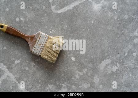 Pennello da decoratore per la pittura di muri. Composizione piatta con spazio per la copia su pavimenti in cemento o cemento con tratti di vernice. Foto Stock