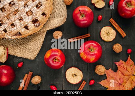 Deliziosa torta di mele fatta in casa, con mele, cannella, noci e foglie autunnali. Cena del giorno del Ringraziamento composizione piatta su un tavolo di legno. Foto Stock