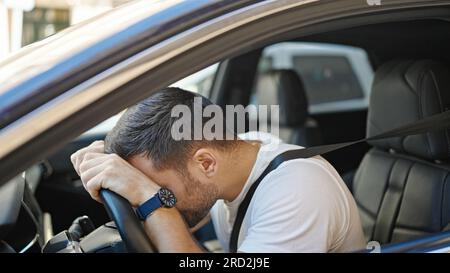 Giovane uomo ispanico ha sottolineato la guida di auto in strada Foto Stock