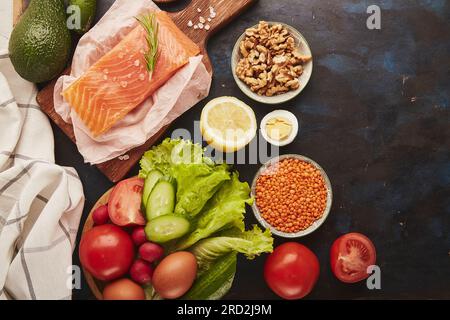 Ketogenic, Paleo, FODMAP, concetto di dieta. Frutta, verdura, salmone affumicato, verdure su una superficie nera di legno Foto Stock