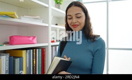 Giovane donna ispanica bella studente in piedi libro di lettura in classe universitaria Foto Stock