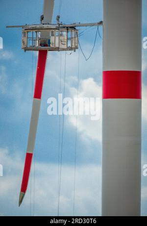 Radegast, Germania. 18 luglio 2023. Una piattaforma di lavoro è appesa a una pala del rotore di una nuova turbina eolica nel cantiere di una nuova centrale eolica. L'espansione delle turbine eoliche onshore sta facendo progressi in Germania. Nella prima metà del 2023 furono erette 331 turbine eoliche con una capacità totale di circa 1,56 gigawatt. Credito: Jens Büttner/dpa/Alamy Live News Foto Stock