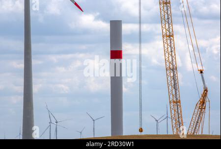 Radegast, Germania. 18 luglio 2023. Una gru lavora nel cantiere di un nuovo parco eolico. L'espansione delle turbine eoliche onshore sta facendo progressi in Germania. Nella prima metà del 2023 furono erette 331 turbine eoliche con una capacità totale di circa 1,56 gigawatt. Credito: Jens Büttner/dpa/Alamy Live News Foto Stock