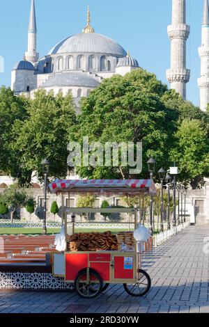 Moschea Sultan Ahmed, nota anche come Moschea Blu, a Sultanahmet, Istanbul, Turchia. Più posti a sedere e un distributore automatico rosso con Simits, alias bagel turchi Foto Stock