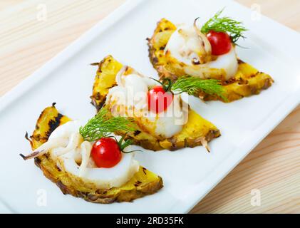 Immagine della seppia fritta su un grill con ananas, pomodori ciliegini e salsa Cile Foto Stock