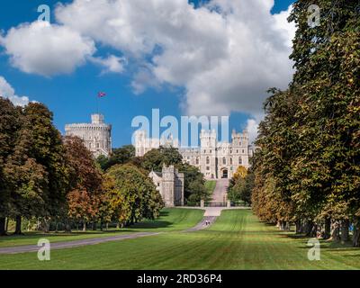 Il Castello di Windsor e la lunga passeggiata con bandiera Union Jack, nei colori estivi/autunnali con gli escursionisti nel cielo blu e le nuvole di luce del sole, Windsor Berkshire, Regno Unito Foto Stock