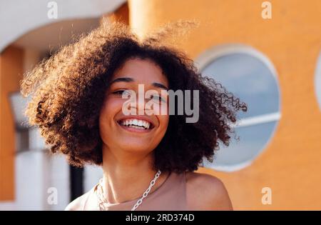 La ragazza adolescente afroamericana felice sorride davvero all'aperto. Un'attraente adolescente dalla pelle scura sta camminando lungo la strada della città. Ora legale. Orano Foto Stock