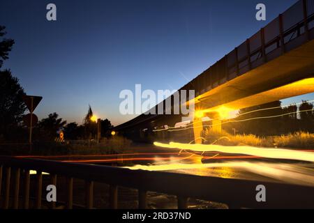 Rotatoria sotto un viadotto nella campagna italiana di notte vista da un marciapiede ai margini di una strada Foto Stock