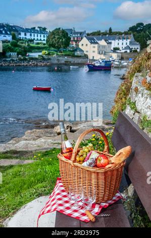 PICNIC FRANCE BRETAGNA DOELAN FINISTERE panchina da picnic all'aperto vista mare paesaggio del porto con barche da pesca a Doëlan Finistere Bretagna Francia Foto Stock