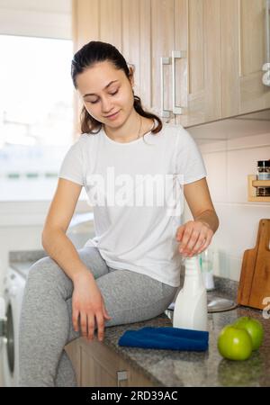 Giovane donna positiva che si prepara a pulire la cucina Foto Stock