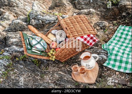 Cestino da picnic con baguette, formaggio e vino rosè, uva 7 mele al mare, vacanza francese. Doëlan Finistere Bretagna Francia Foto Stock