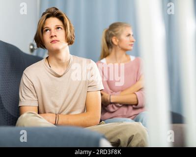 Un adolescente sconvolto seduto sul divano dopo aver litigato con la madre Foto Stock