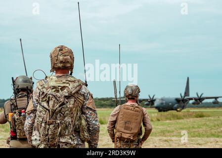 Un membro delle forze speciali lituane, un membro lettone delle forze operative speciali e un membro statunitense Air Force Combat Controller assegnato al 352d Special Operations Wing controlla un aereo da atterraggio durante l'addestramento Special Operations Air-Land Integration vicino a Daugavpils, Lettonia, 28 giugno 2023. La prontezza operativa è fondamentale per i partenariati, la risposta alle crisi, la deterrenza e il sostegno agli Alleati e ai partner. Foto Stock